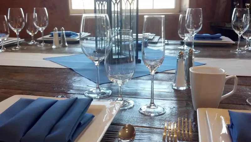 Square white plates with navy napkins, stemware and a black lantern on a dark wood table Square white plates with navy napkins, stemware and a black lantern on a dark wood table