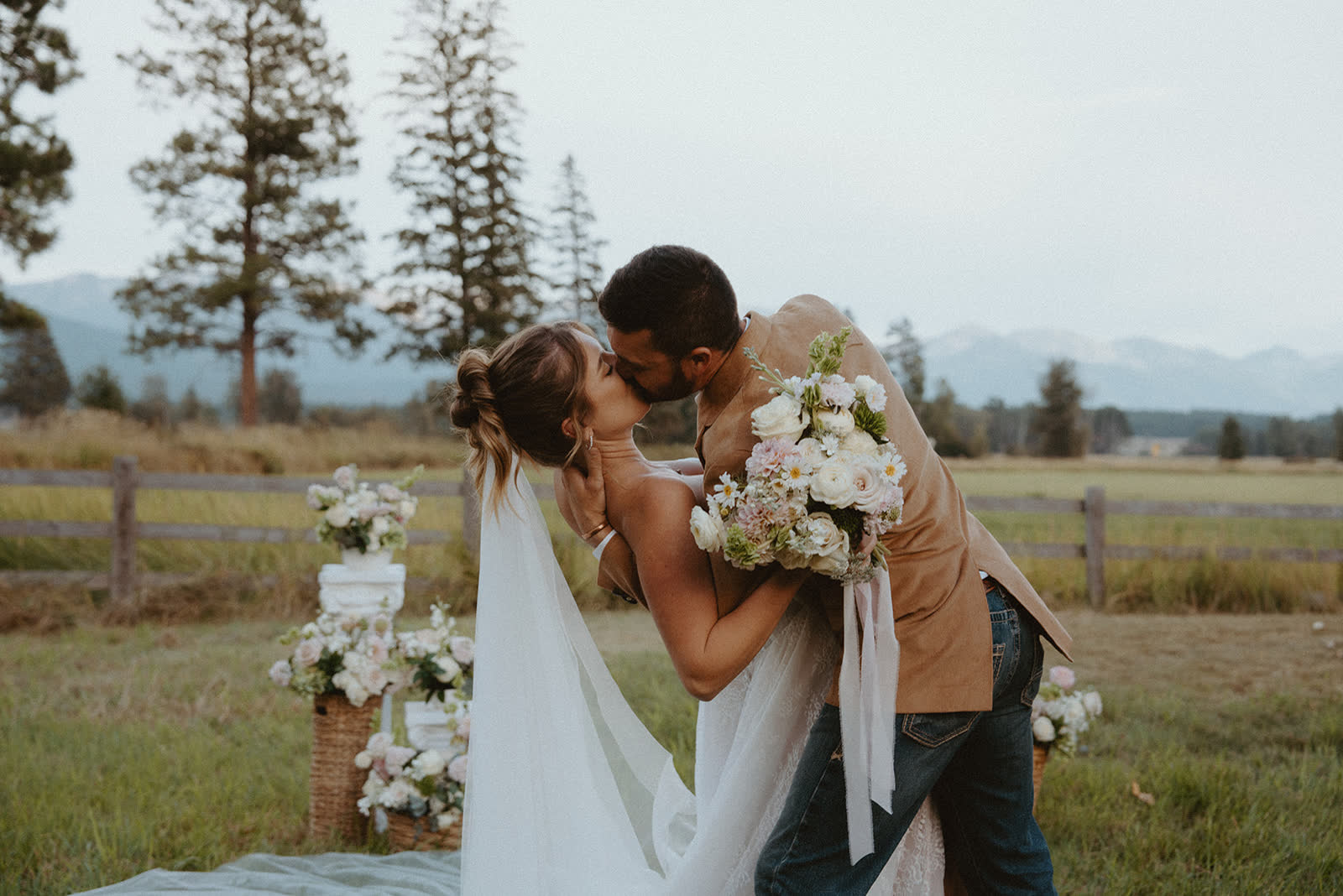 Couple kissing in a mountain meadow after the ceremony