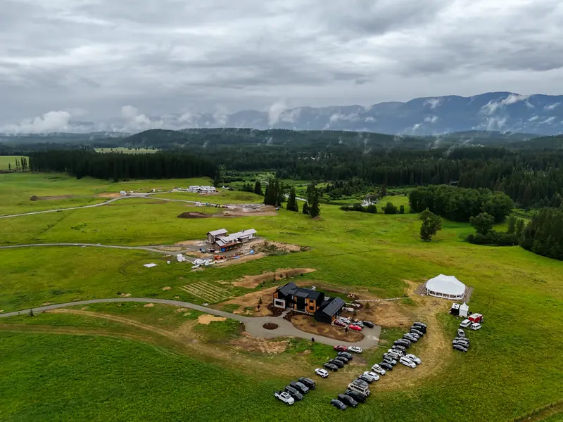 A high aerial view of a mountain valley property with a modern house and a white event tent