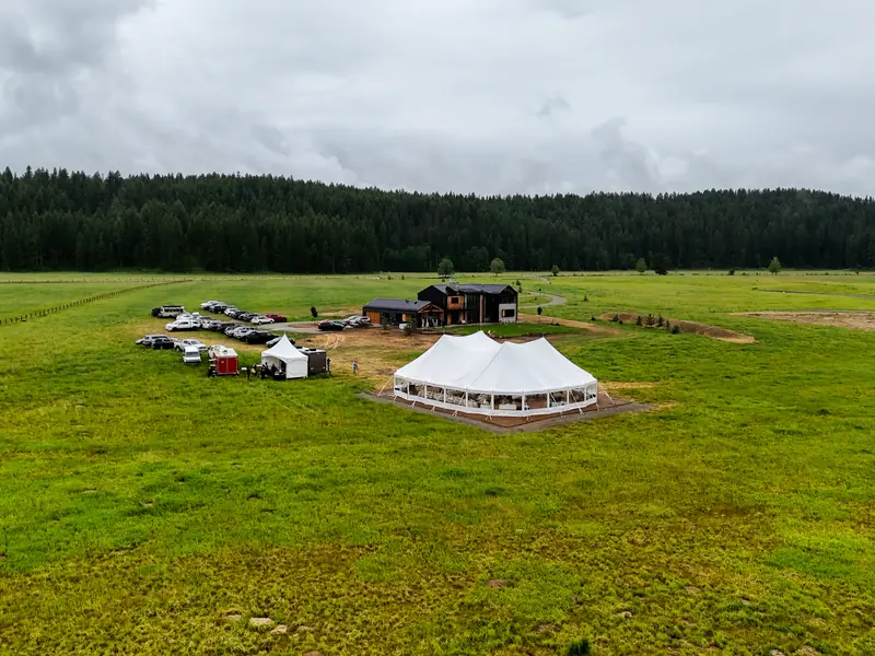 Aerial view of a large white tent pitched in a green rural meadow