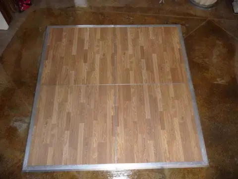 A square New England plank dance floor with a metal edge trim, laid out before an event